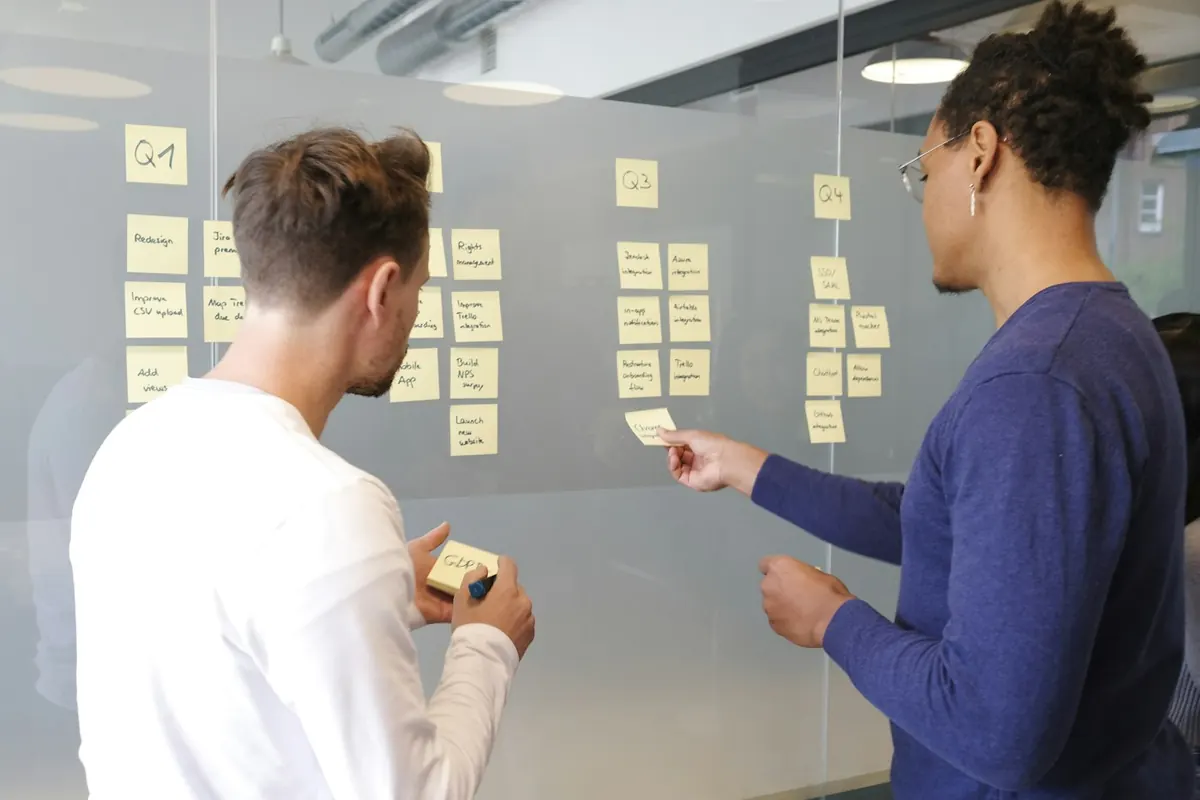 Developer and client mapping a software workflow on a glass wall
